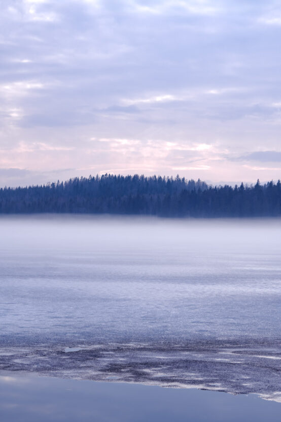 Misty over a forest frozen lake in Sweden