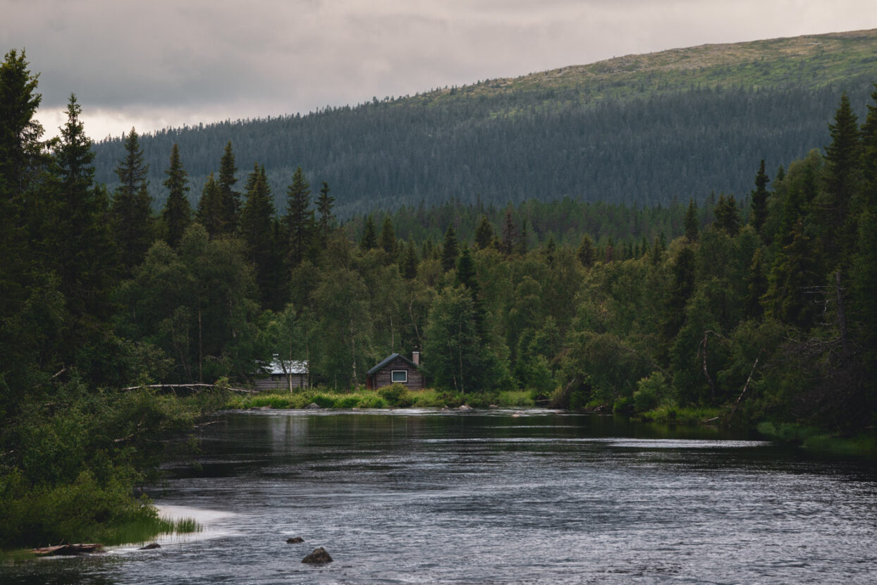 A wooden cabin at By a blue river at the feet of the mountains of North Dalarna