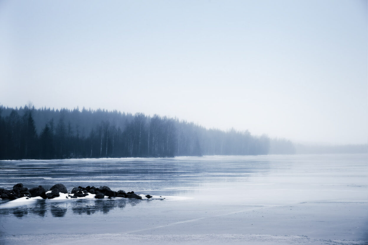 Mist over a frozen forest lake during the Swedish winter