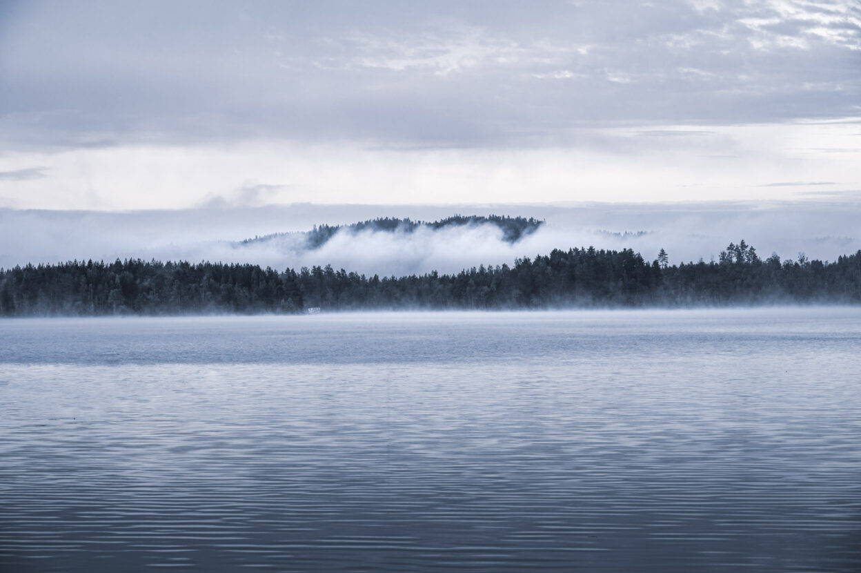 White clouds and mist on a forest lake in Sweden