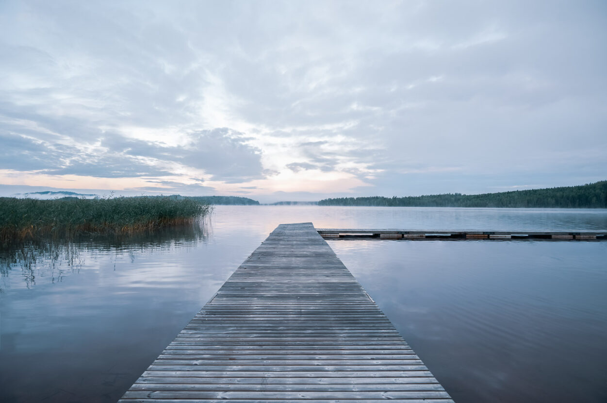 A long wooden jetty on a misty forest lake in Sweden