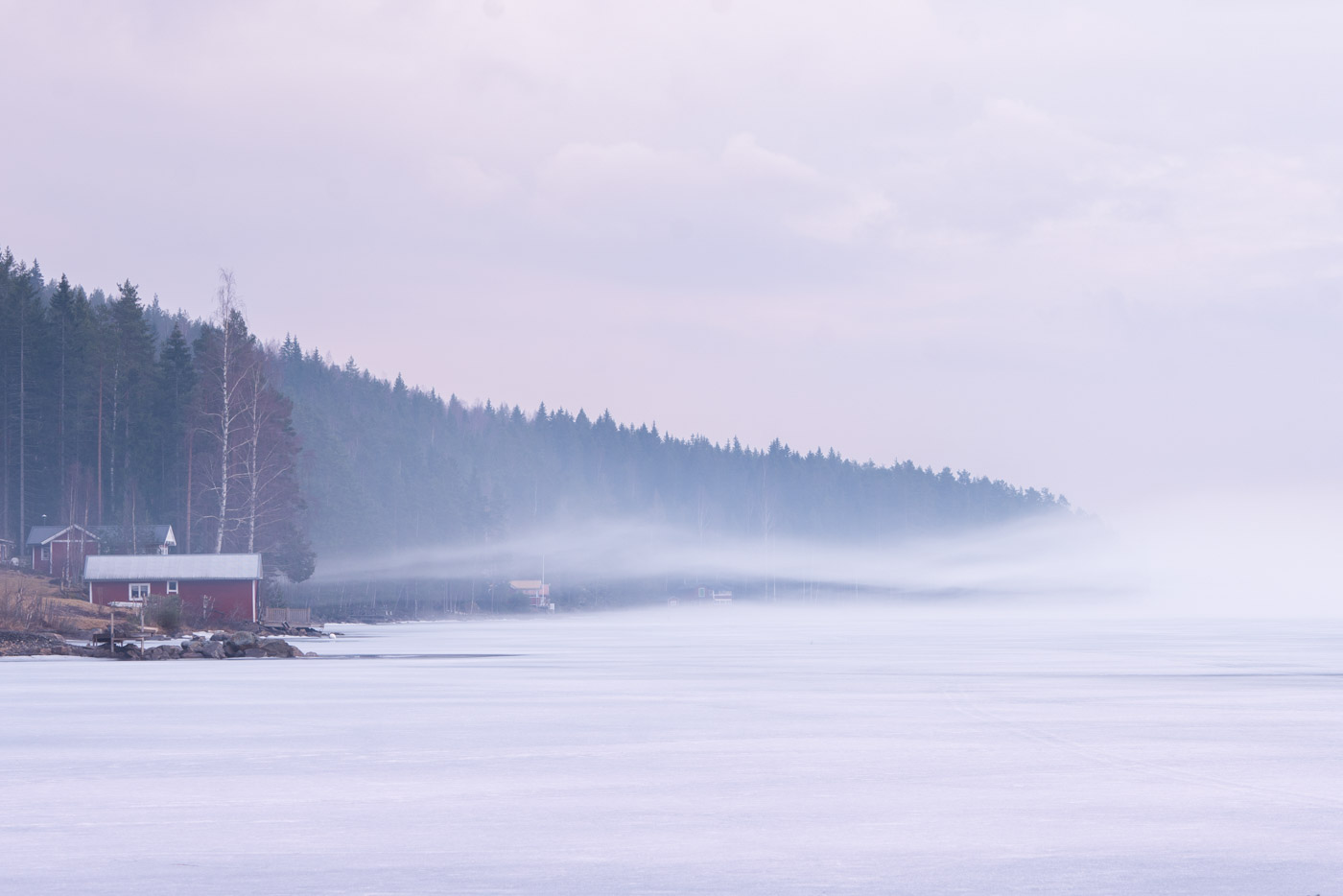 Swedish cabin by a frozen misty lake